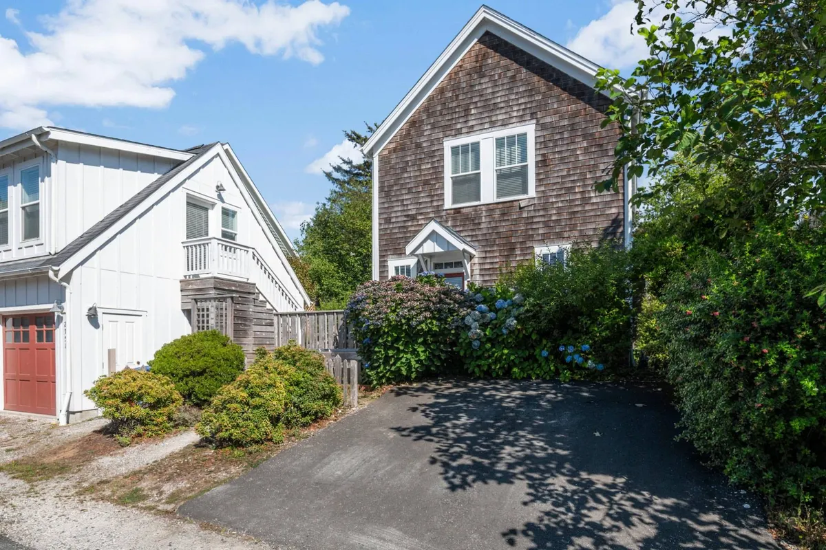 The exterior of the main house and an adjacent bonus building, surrounded by colorful hydrangeas and set on a friendly, open driveway. The setting is lively and inviting, suggesting plenty of space for gatherings, play, and multi-generational family stays.