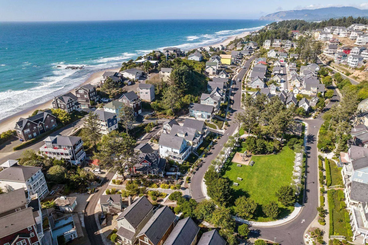 An exterior vantage capturing the expansive ocean view, green park area, and the neighborhood's layout with easy beach access. The scene is bathed in vibrant daylight, evoking a lively, welcoming setting for family outings, nature play, and seaside adventures.